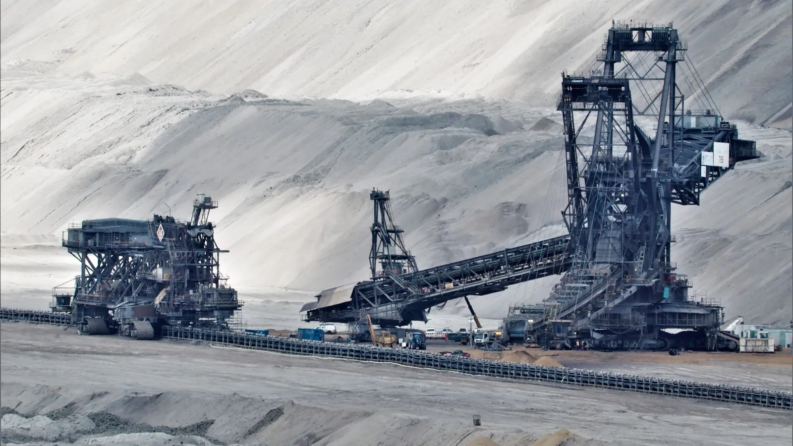 A large bucket wheel excavator operates in a vast industrial mining area, illustrating heavy machinery in action.