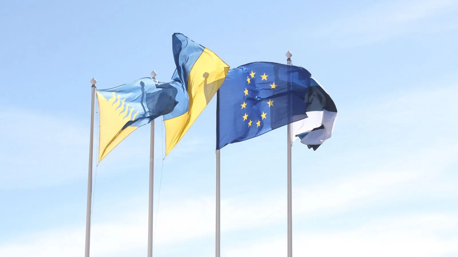 European Union and Estonian flags wave under a clear blue sky, symbolizing unity and harmony.
