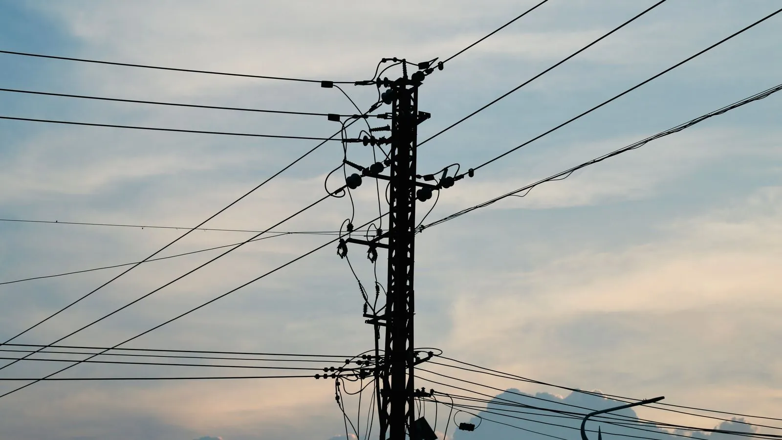Silhouette of power lines and pole against a vibrant sunset sky.