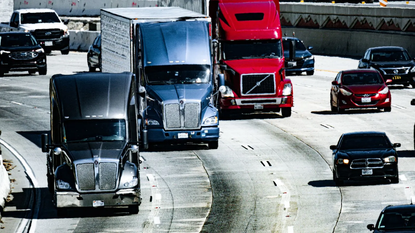 Trucks and cars traveling on a congested city highway during the day.