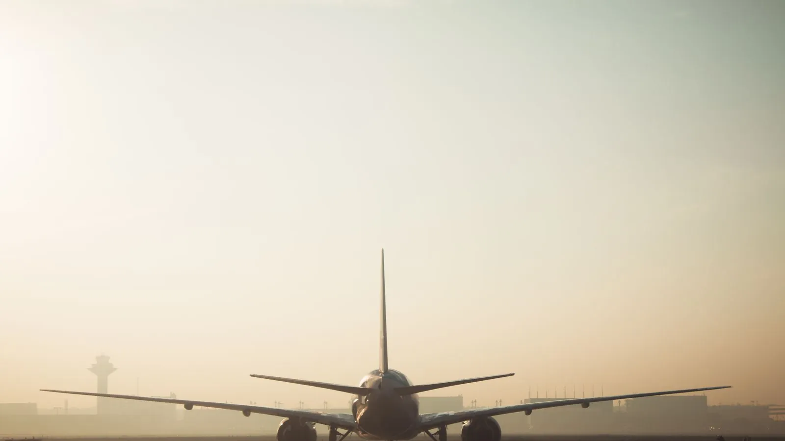 A misty morning scene of a plane on the runway with a hazy sky background, showcasing air travel ambiance.