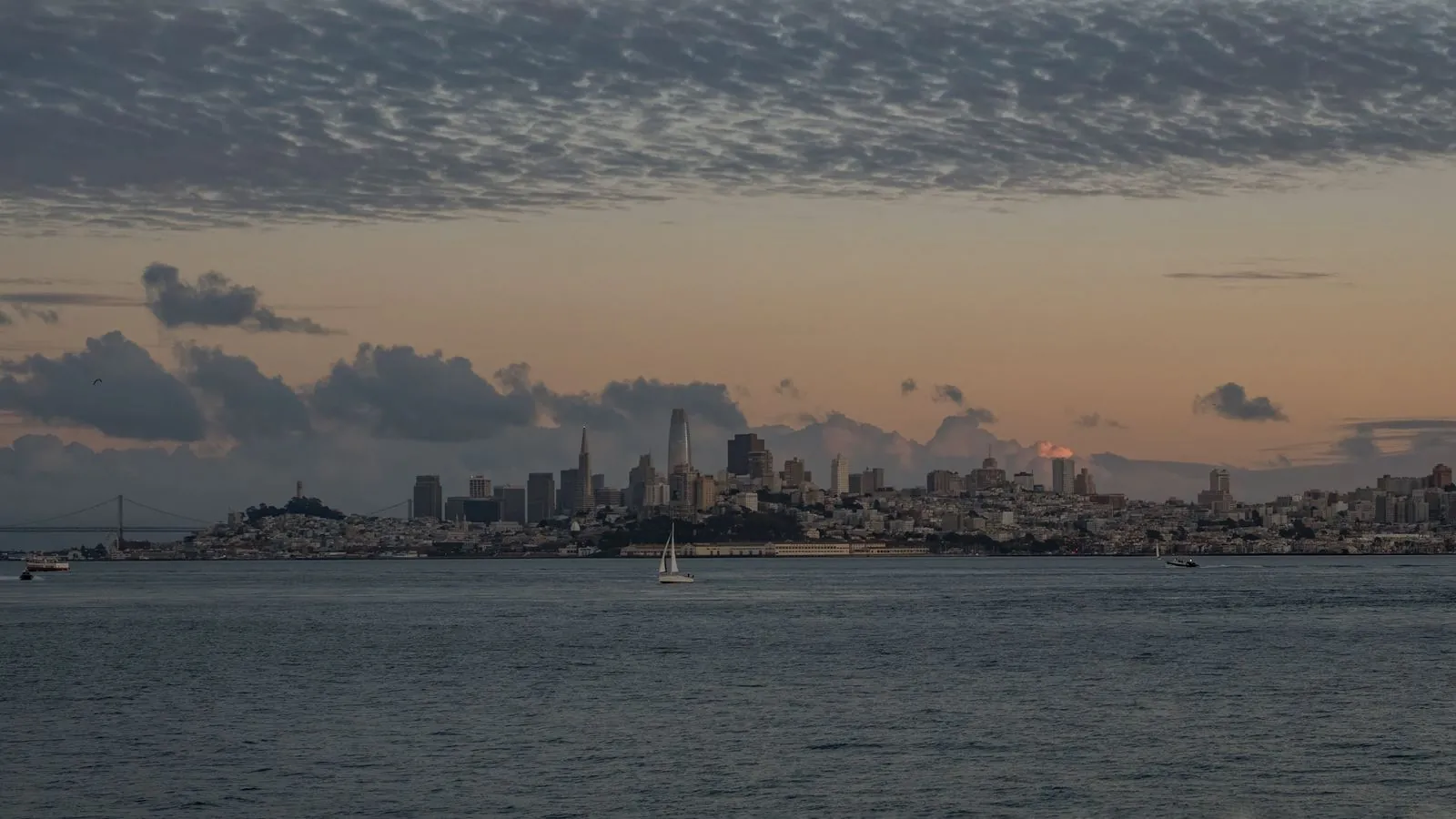 Beautiful view of San Francisco skyline with tranquil waters and a dramatic sunset sky.