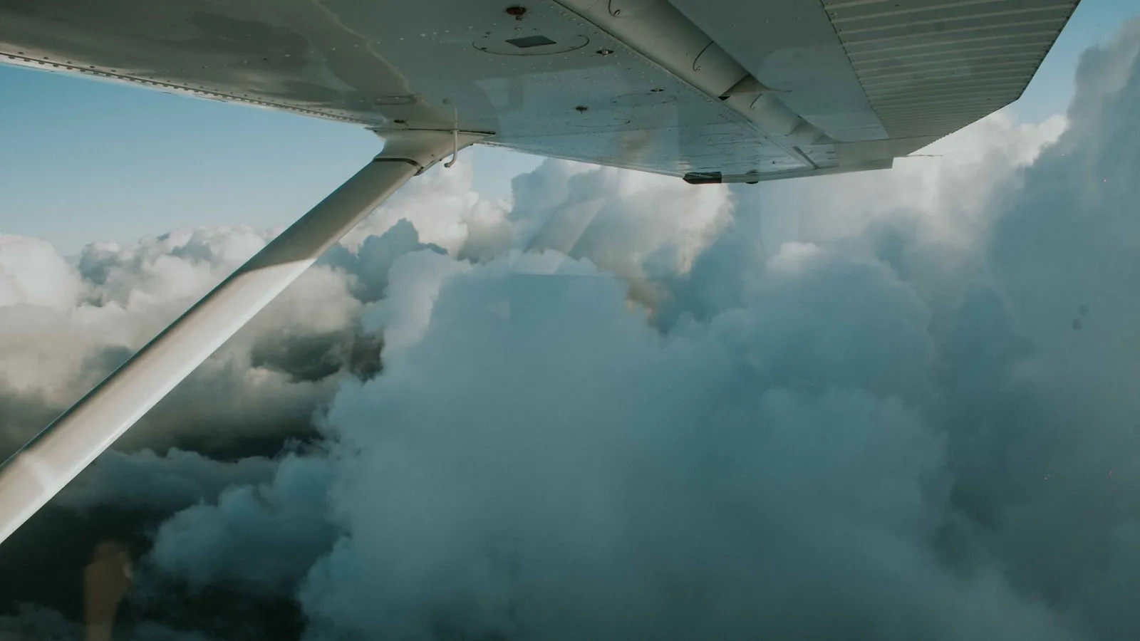 A serene view of dense clouds from an airplane wing, capturing the essence of flight and exploration.