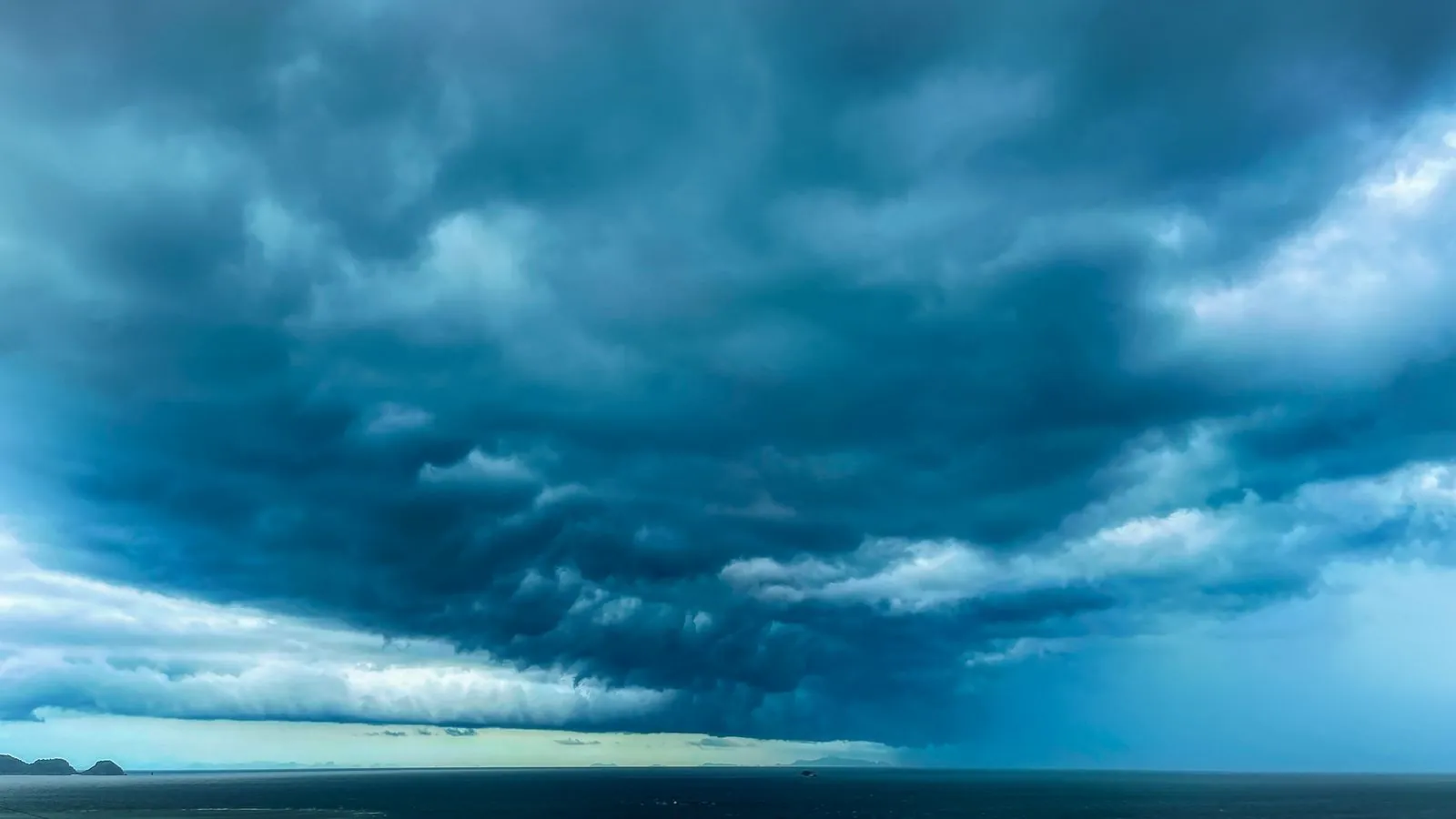 A dramatic formation of dark storm clouds hovering over a vast ocean expanse.