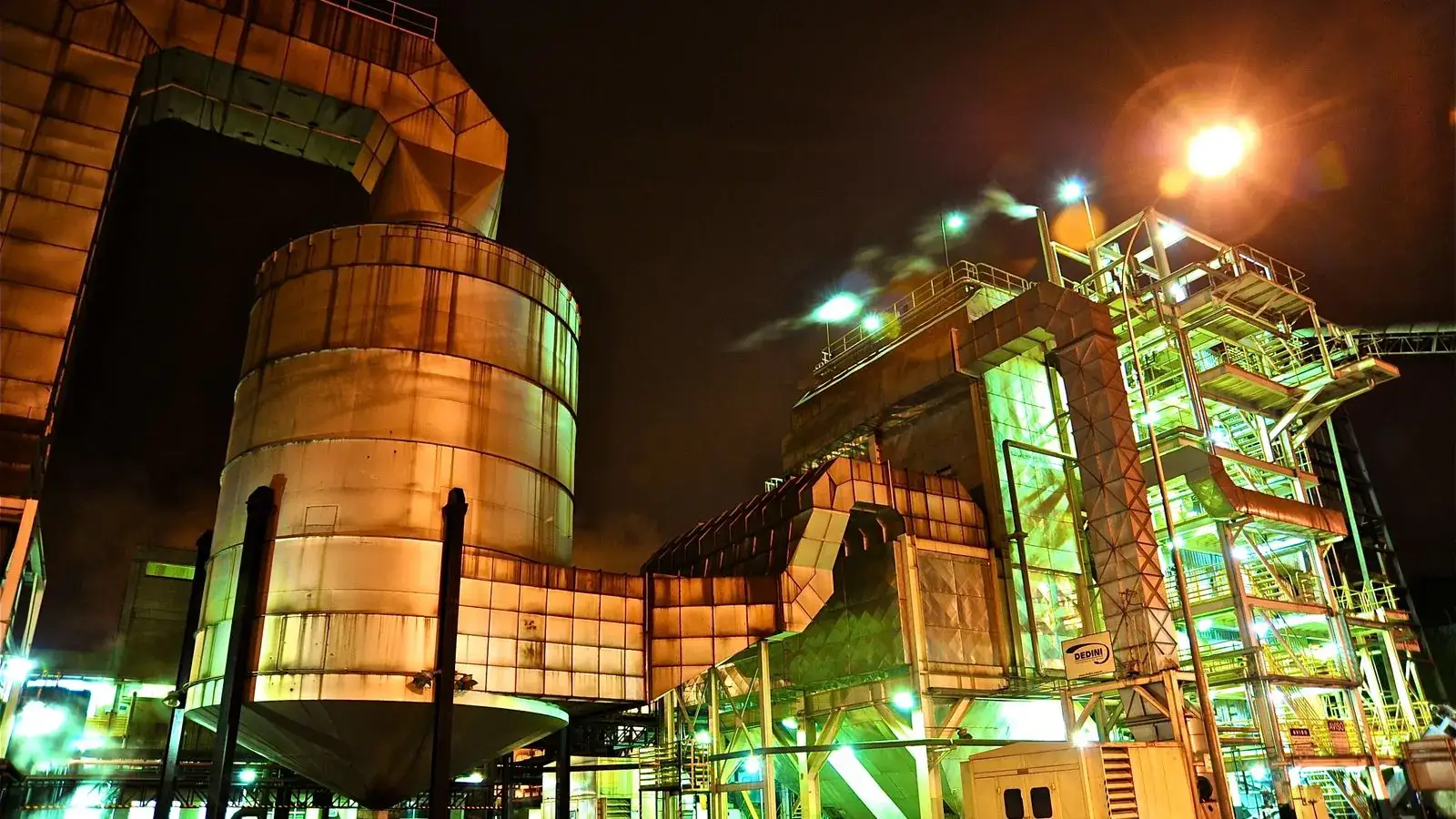 A glowing industrial structure illuminated at night, showcasing complex machinery.